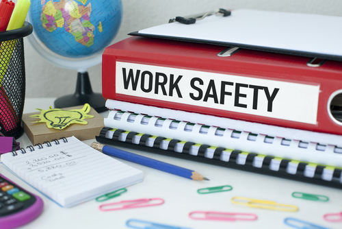 binder with work safety written on it, surrounded by notes, paperclips, other notebooks