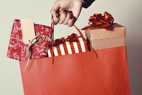 woman holding gift wrapped presents in a shopping bag
