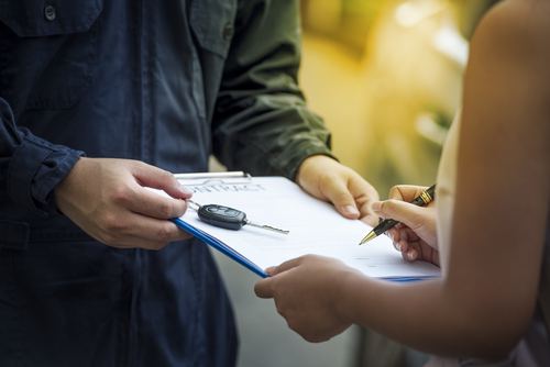 person holding clipboard and car keys, woman signing papers
